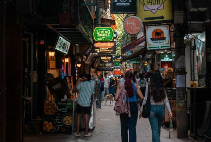 Orang-orang berjalan menyusuri jalan sempit dengan toko-toko dan tanda-tanda.